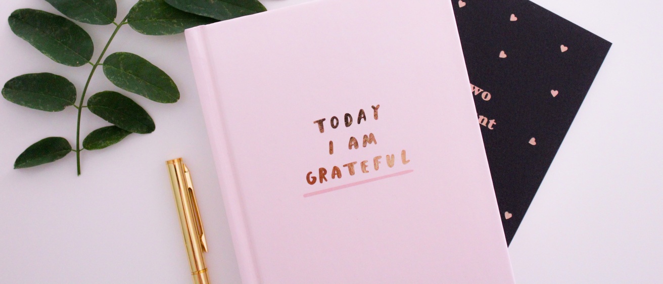 Notebook that says "Today I am Grateful" with a plant, pen and paper