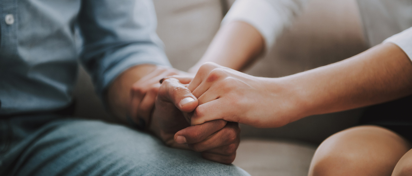 Photo of two people's hands clasped.