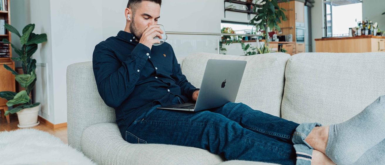 person sitting on couch with computer and coffee