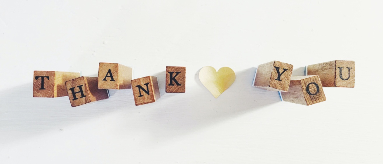 Wooden blocks that spell out "Thank you" with a paper heart in between the words