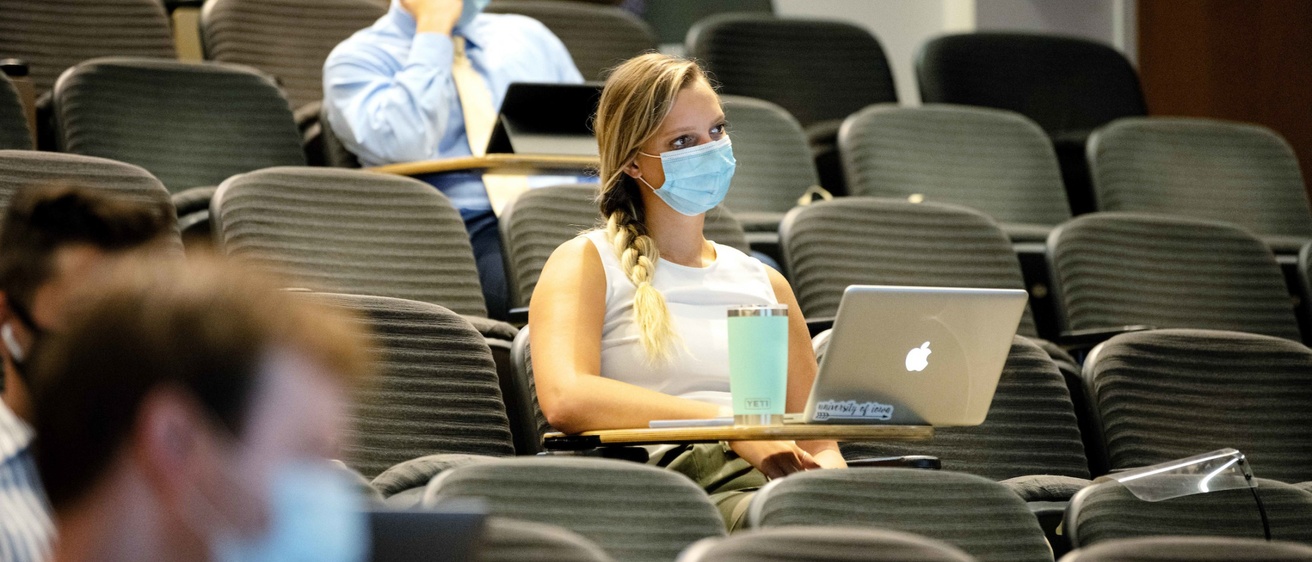Students sitting in a lecture hall wearing PPE