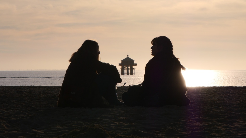 Two people sitting on a beach talking