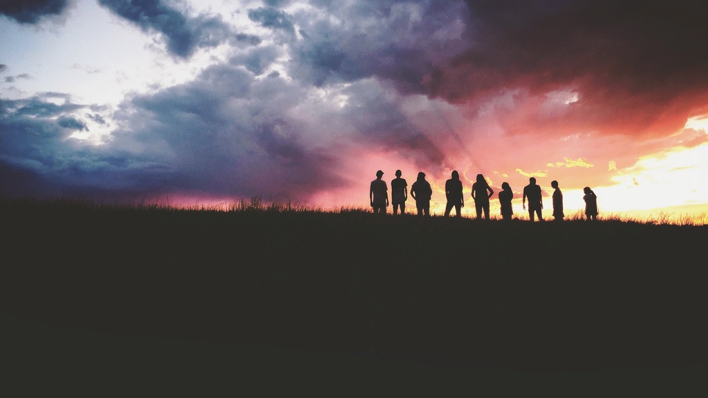 A group of people standing in front of a sunset