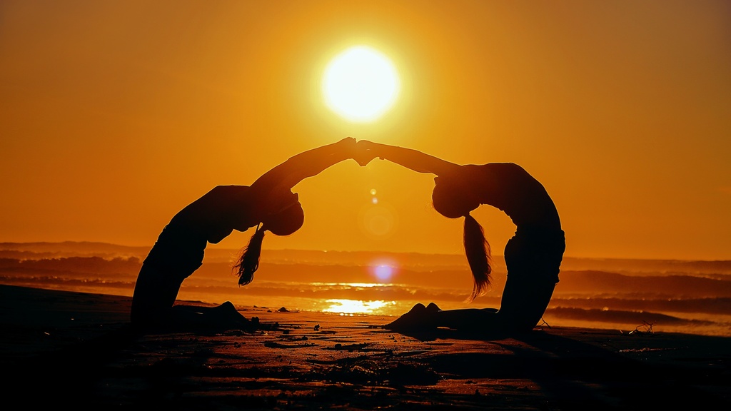 Two people in a yoga pose at sunset