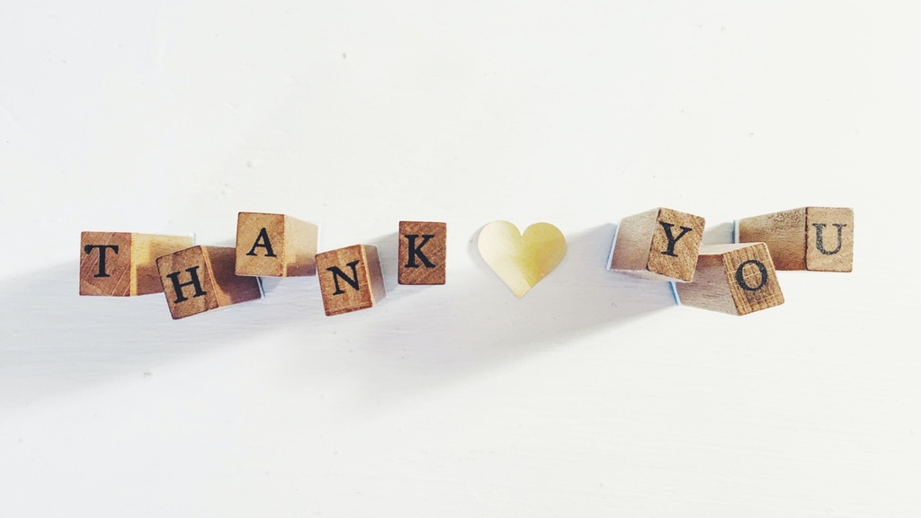 Wooden blocks that spell out "Thank you" with a paper heart in between the words