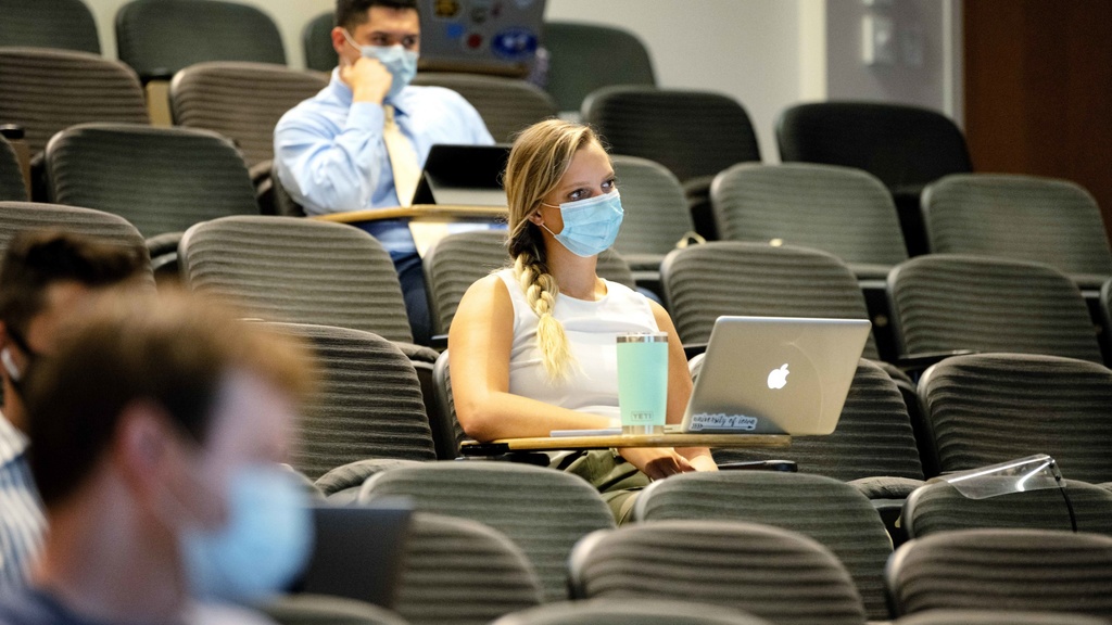 Students sitting in a lecture hall wearing PPE